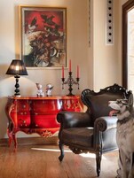 A room with a red wooden cabinet, a black leather chair, and a painting on the wall.