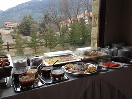 A buffet with various food items and a scenic view through a window.