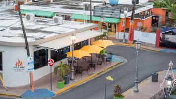 A street view with a restaurant patio, outdoor seating, and a 'NO ENTRY' sign.