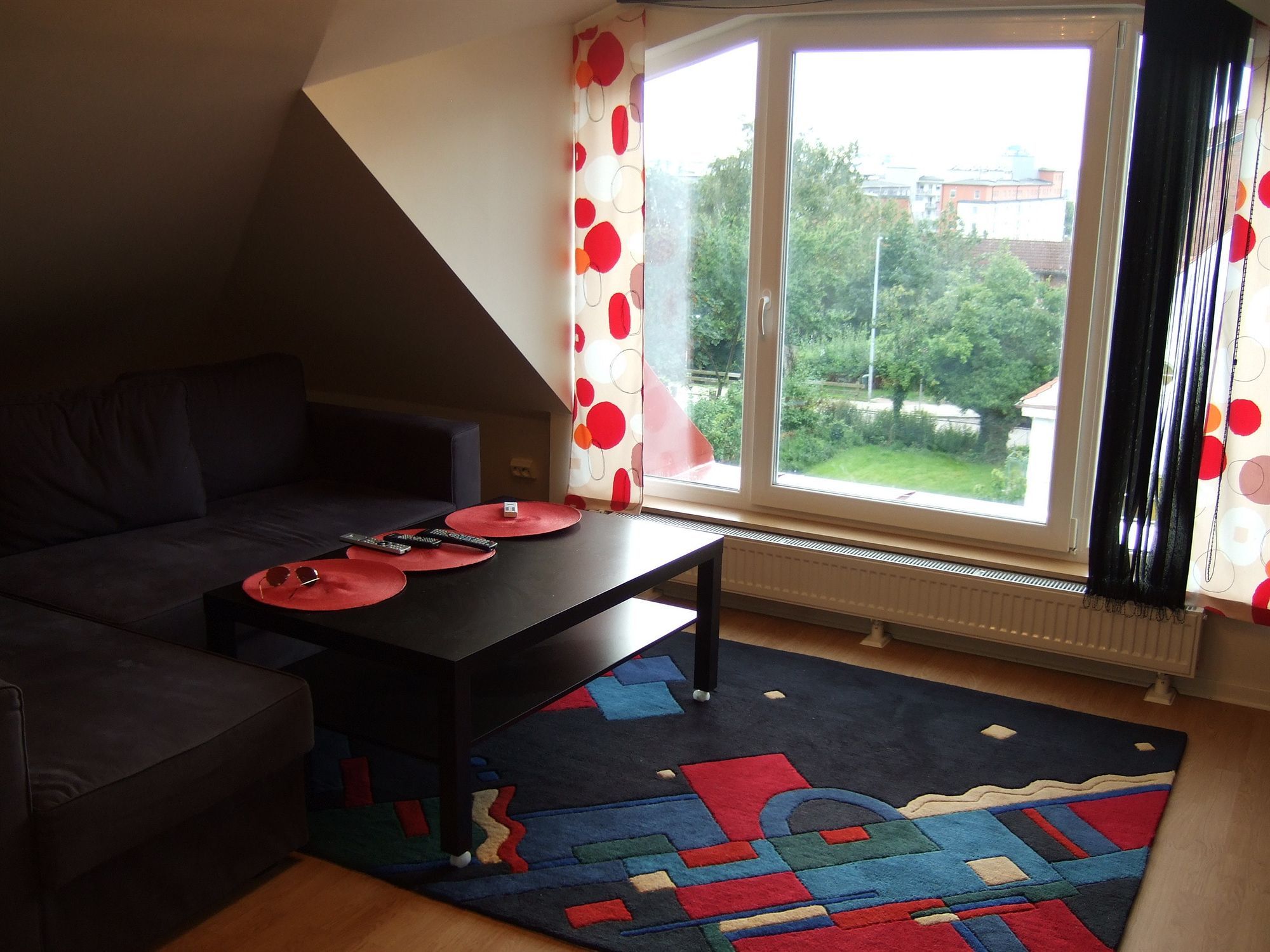 A modern living room with a dark sofa, a black coffee table, and a colorful rug.