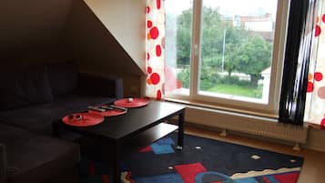 En moderne stue med en mørk sofa, et sort sofabord og en farverig måtte.