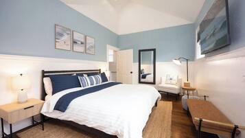 A bedroom with a bed, bedside tables, a chair, a bench, and artwork on the walls.