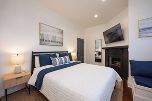 A hotel room with a bed, bedside tables, a fireplace, and artwork on the walls. - Zaballa House (Half Moon Bay)
