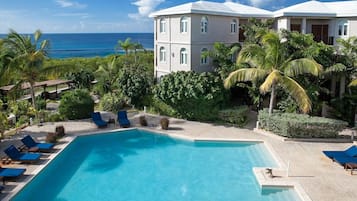 Un resort con piscina, sillas de descanso y vista al océano.