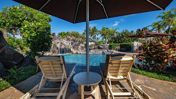 A poolside area with two lounge chairs, a table, and an umbrella. - The Islands at Mauna Lani (Kamuela)