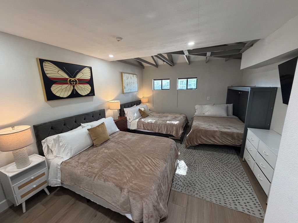 A hotel room with two beds, a desk, a wardrobe, and a television.