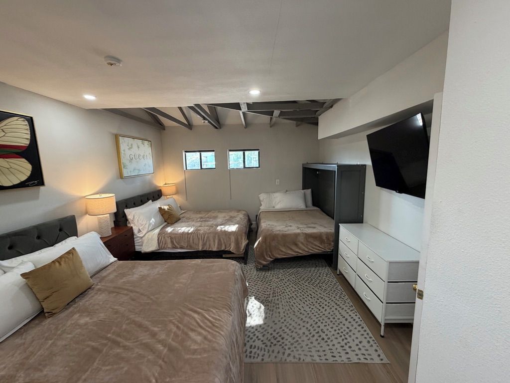 A hotel room with two beds, a TV, and a desk.