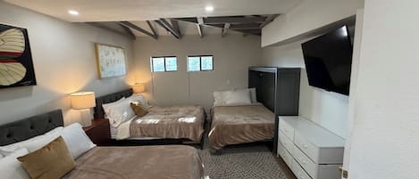 Quarto de hotel com duas camas, televisão e escrivaninha.