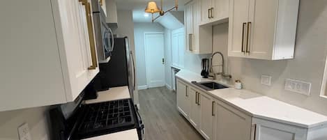 A kitchen with white cabinets, a black stove, and a sink.