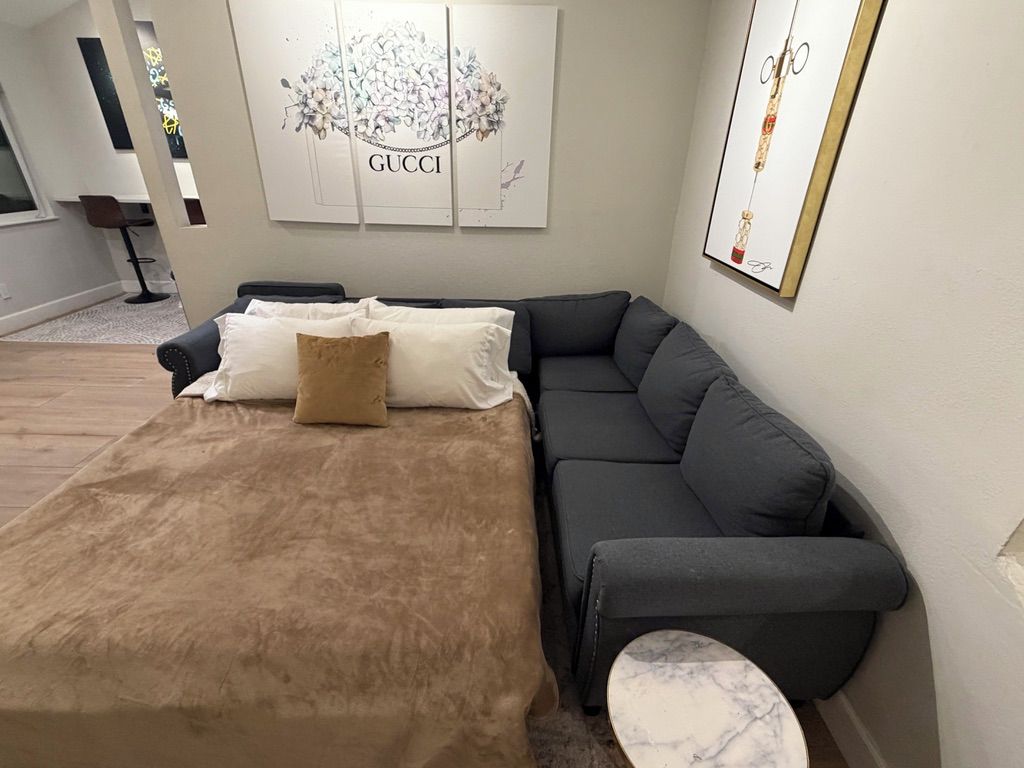 Un salon moderne avec un canapé, une petite table et des œuvres d’art accrochées au mur.