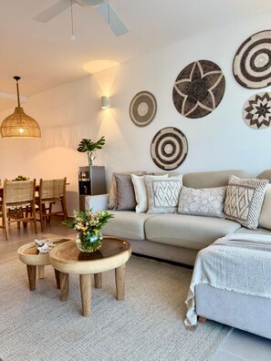 A modern living room with a sofa, coffee table, and wall art. - PUNTA CANA OASIS WITH PRIVATE PICUZZI JUST A 2 MINUTE WALK FROM BAVARO BEACH! (Punta Cana)