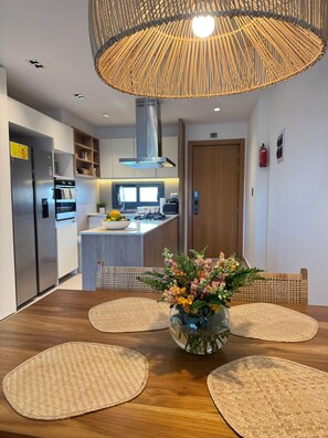 Une cuisine moderne dotée d’un îlot central, d’appareils électrom énagers en acier inoxydable et d’un luminaire suspendu.