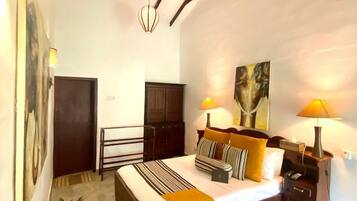 A bedroom with a bed, bedside tables, a ceiling fan, and a painting on the wall.