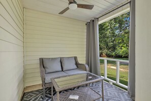 A covered porch with a wicker sofa and a glass table, overlooking a grassy yard. - Newly Renovated, "Daisy" 3 Bedroom, 2 Bath Home! (Hanceville)