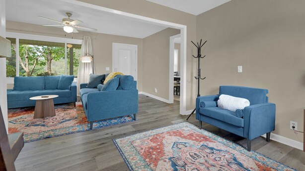 A living room with two blue sofas, a coffee table, a patterned rug, and a ceiling fan. - Newly Renovated, "Daisy" 3 Bedroom, 2 Bath Home! (Hanceville)