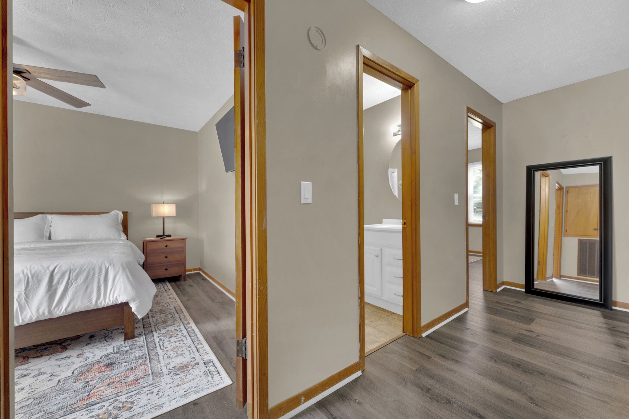 A bedroom with a bed, nightstand, lamp, and a patterned rug.