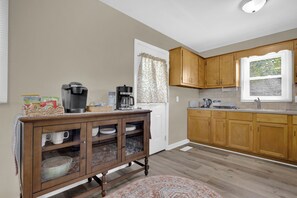 A kitchen with wooden cabinets, a coffee maker, a toaster, and a window with blinds. - Newly Renovated, "Daisy" 3 Bedroom, 2 Bath Home! (Hanceville)