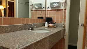 A bathroom with a granite countertop, two sinks, a hairdryer, and a telephone. - Americas Best Value Inn Liberal (Liberal)