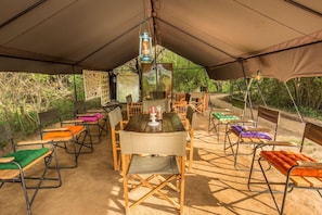 A covered outdoor seating area with a table and chairs, surrounded by trees. - Big Game Camp Udawalawe (Sri Lanka)