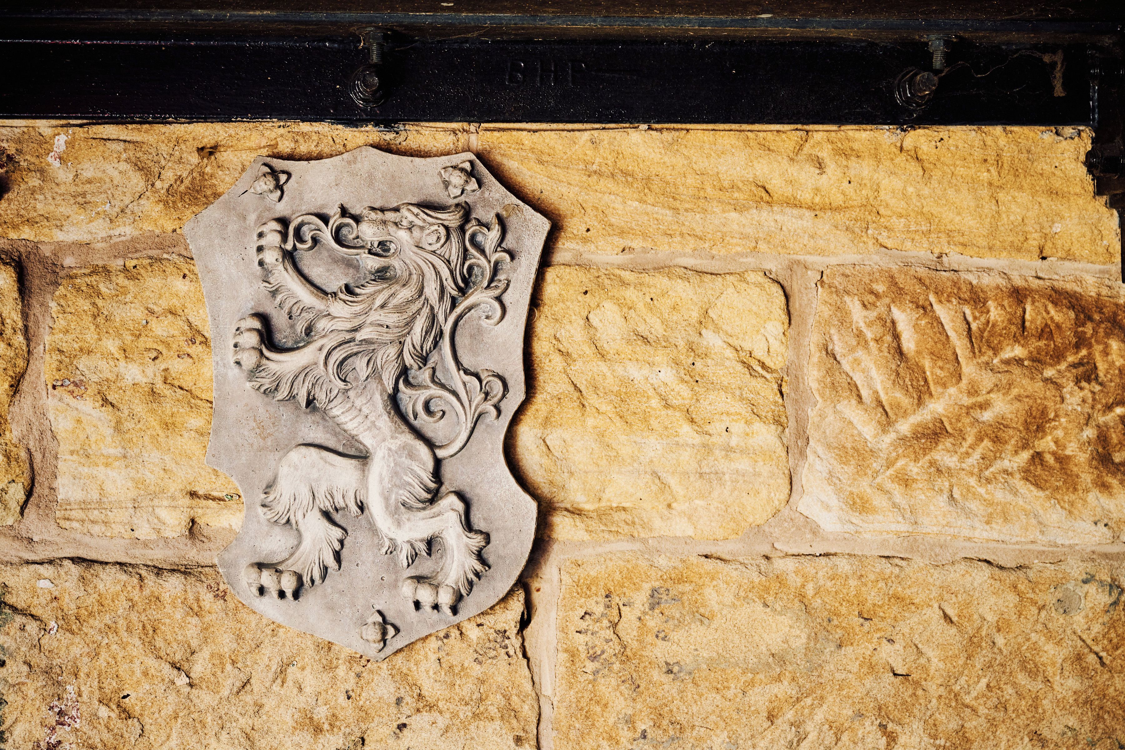 A stone wall with a carved shield emblem.