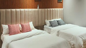 Habitació d'hotel amb dos llits, un amb capçalera de fusta, i dos quadres penjats a la paret.