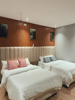 Ett hotellrum med två sängar, en sänggavel i trä och två tavlor som hänger på väggen.