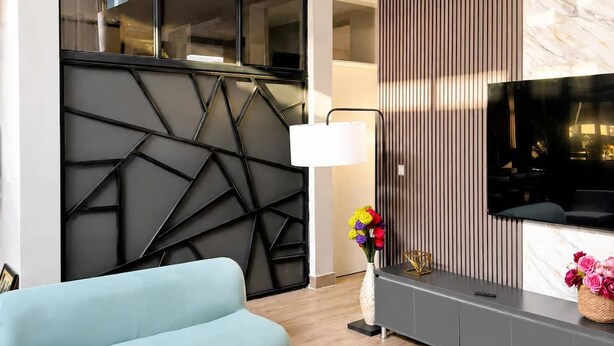 Un saló modern amb un sofà, televisió i un panell decoratiu a la paret.