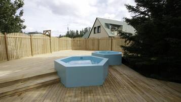 A wooden deck with two large, light-colored rectangular hot tubs.