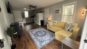 A living room with a yellow sofa, a patterned rug, and a wooden bench. - Perfect 1-bed house near downtown and Garden of the Gods Pet Friendly (Colorado Springs)