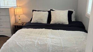 A bedroom with a bed, a nightstand with a lamp, and a window with blinds. - Perfect 1-bed house near downtown and Garden of the Gods Pet Friendly (Colorado Springs)