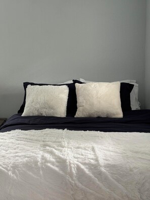 A bed with a white fluffy blanket and black pillows. - Perfect 1-bed house near downtown and Garden of the Gods Pet Friendly (Colorado Springs)