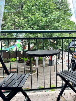 A balcony with a view of a street, a trash bin, and a sign that reads 'Duluth.' - Sunny Corner Heart Of Plateau (Montréal)