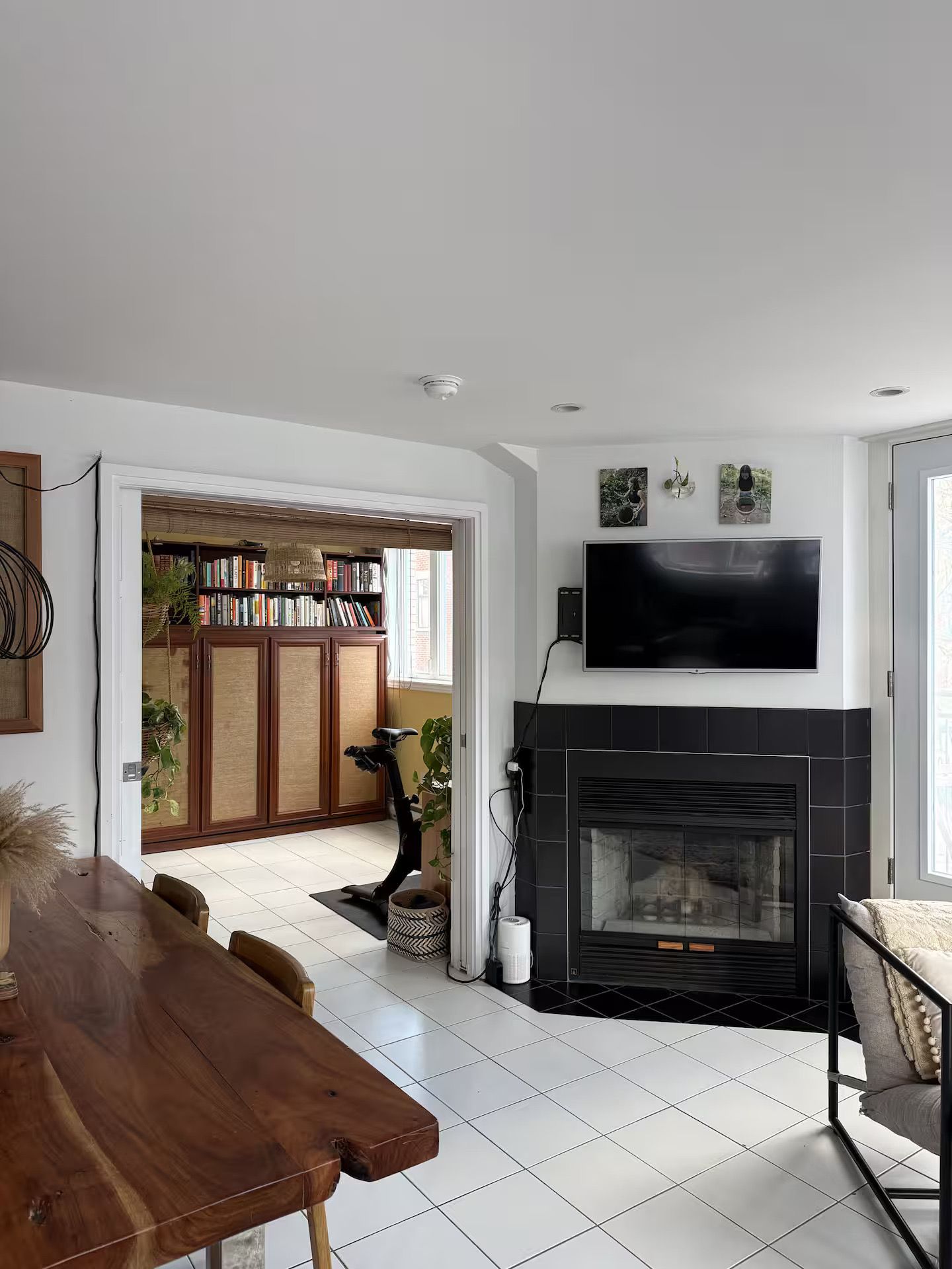 A modern living room with a fireplace, a flat-screen TV mounted above it, and a bookshelf filled with books.
