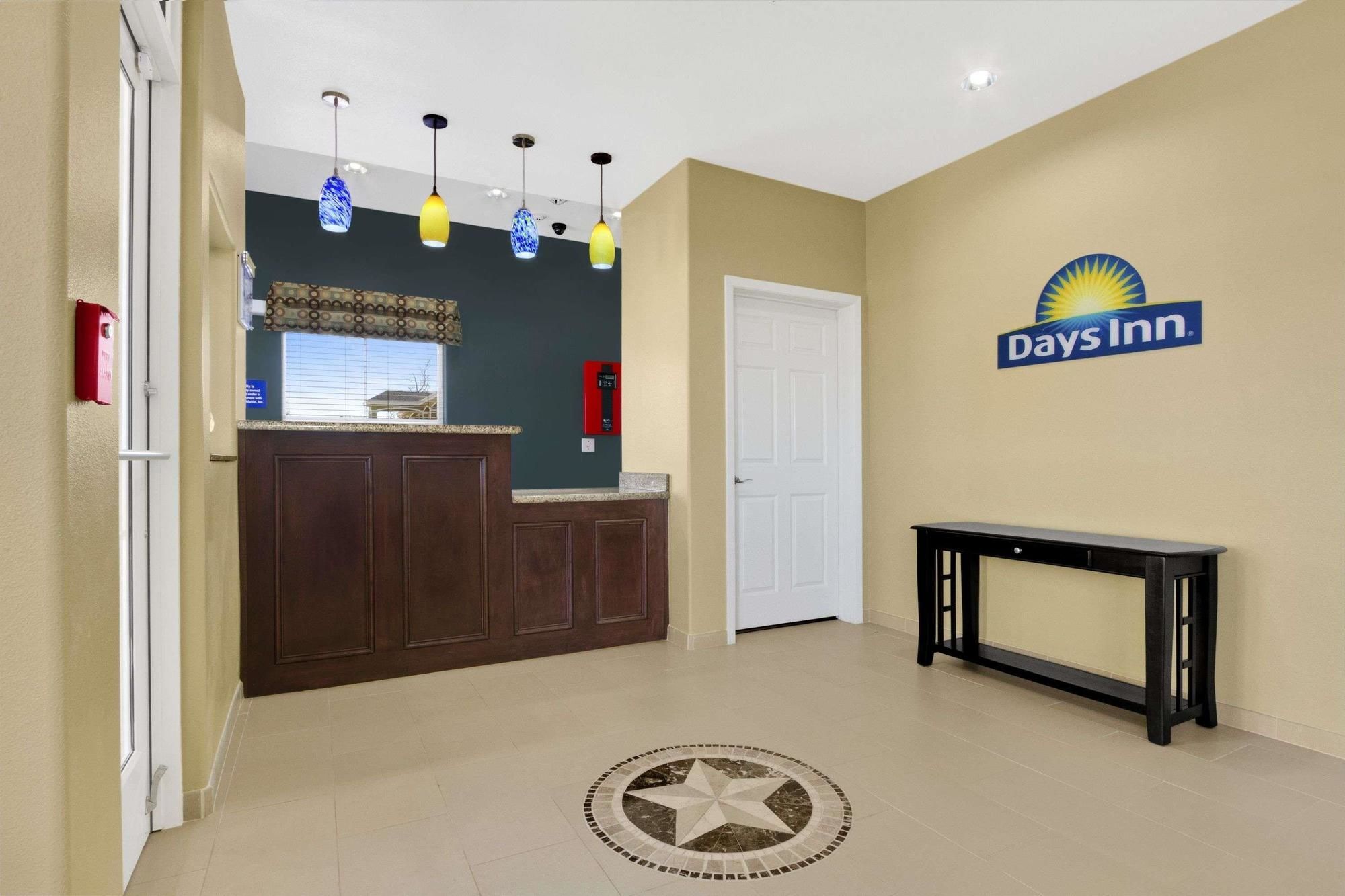 A hotel lobby with a reception desk, a wall-mounted sign for Days Inn, and a decorative floor pattern.
