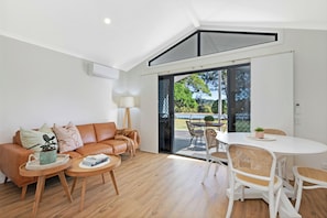 Uma sala de estar moderna com sofá, mesa de centro e área de jantar.