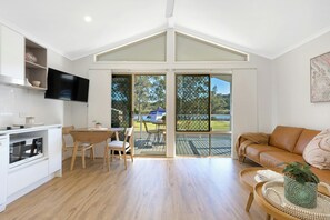 A modern kitchen with a dining area, a sofa, and a view of the outdoors. - Reflections Holiday Park Ferry Reserve (Brunswick Heads)