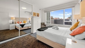 A modern bedroom with a large bed, a mirror, and a view of the outside. - Staycentral - Brunswick Vibe Parkville (Melbourne)