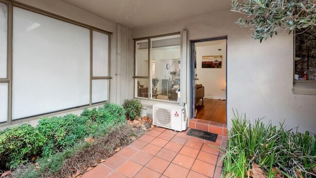 A residential entrance with a tiled patio, a glass door, and a small air conditioning unit. - Staycentral - Brunswick Vibe Parkville (Melbourne)