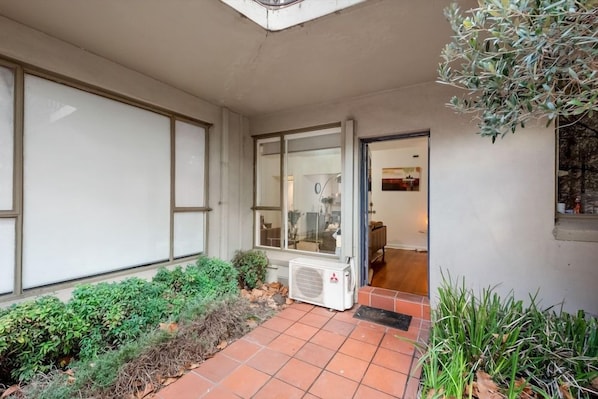 A residential entrance with a tiled patio, a glass door, and a small air conditioning unit. - Staycentral - Brunswick Vibe Parkville (Melbourne)
