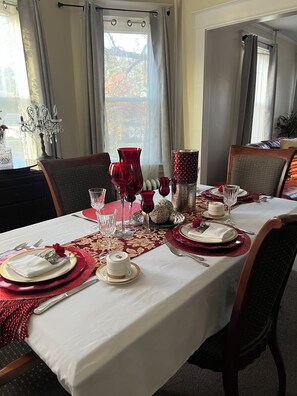 A dining table set with red and white tableware, surrounded by chairs.