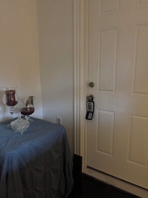 A room with a closed door, a table with a blue tablecloth, two wine glasses, and a crystal decanter.