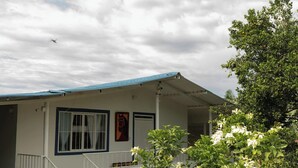 Ein einstöckiges Haus mit blauem Dach, einer Veranda und einer Treppe, die zum Eingang führt.