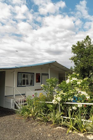Een gelijkvloers huis met een blauw dak, een veranda en een trap naar de ingang.