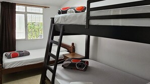 Ein Schlafraum mit Etagenbett, Fenster, Schreibtisch und Stuhl.