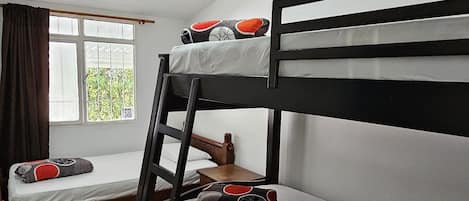 A bunk bed room with a window, a desk, and a chair.