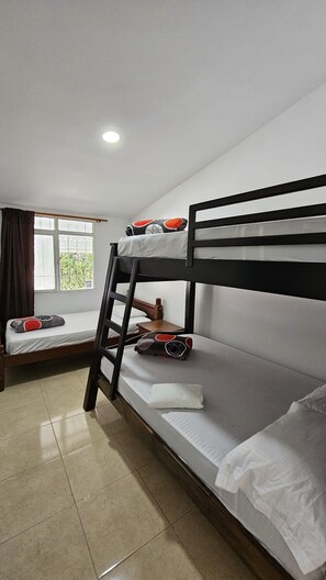 Een slaapkamer met een stapelbed, een raam, een bureau en een stoel.