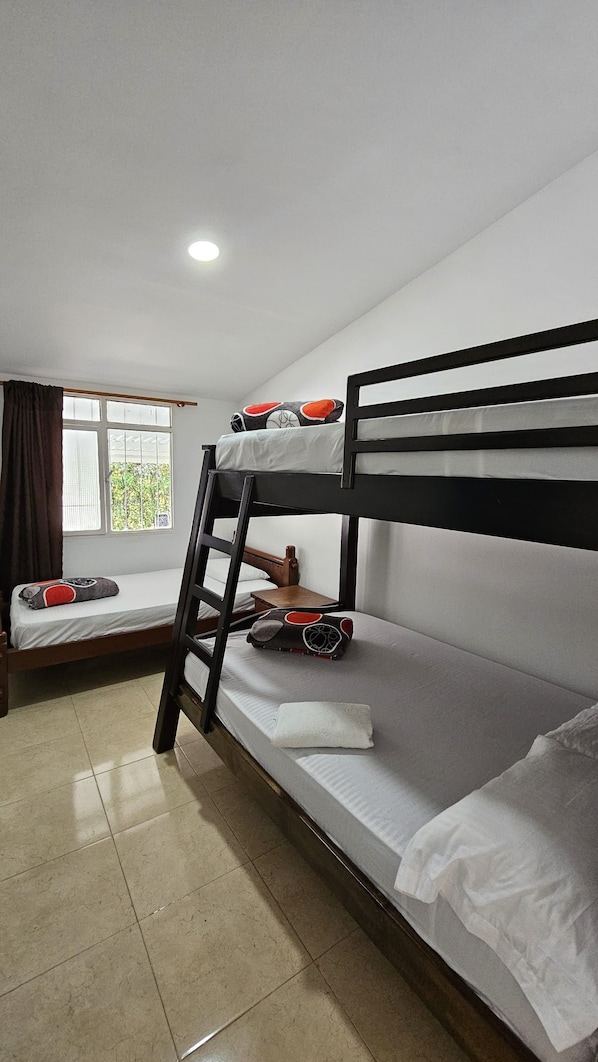 A bunk bed room with a window, a desk, and a chair.