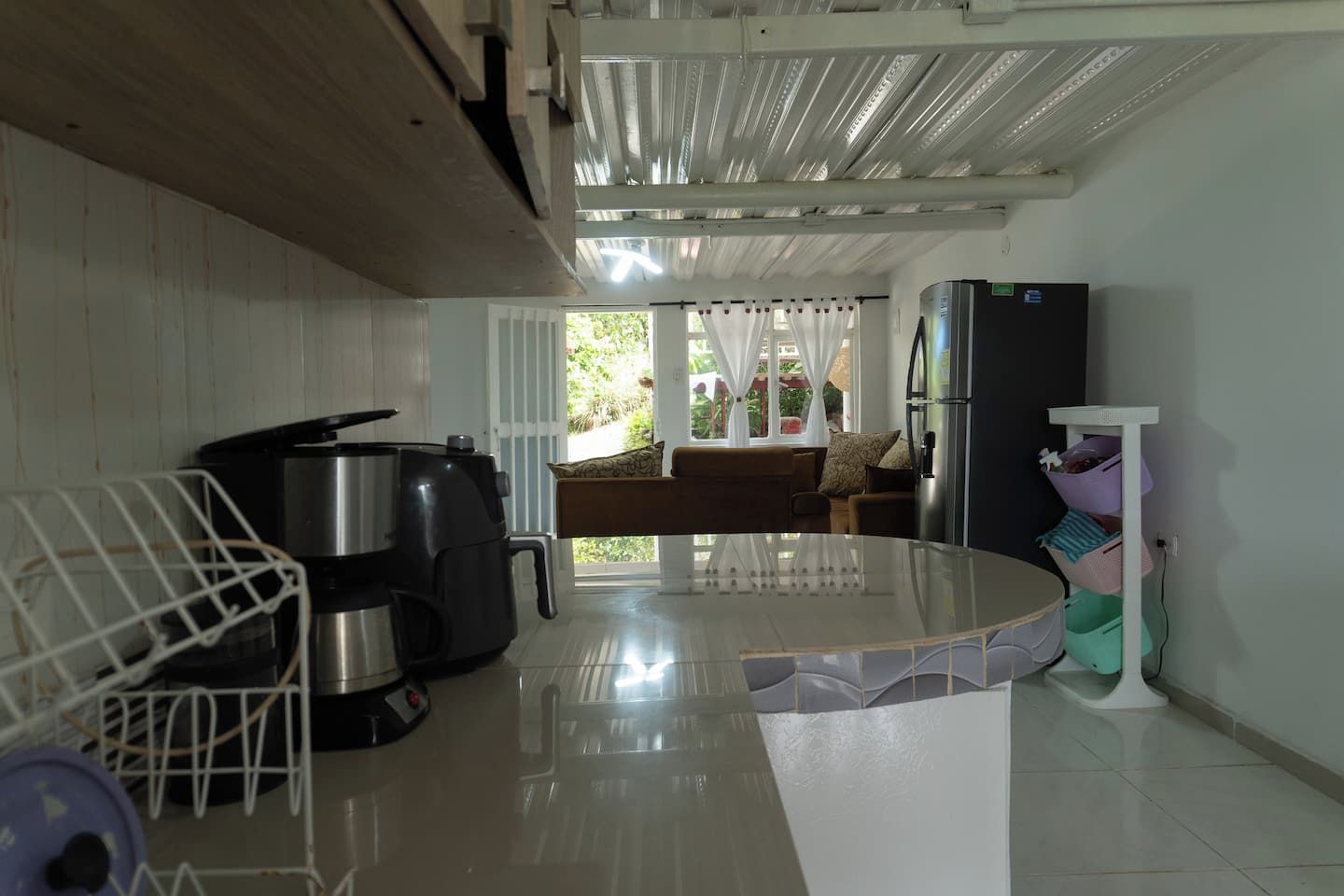 A kitchen with a coffee maker, a kettle, and a refrigerator.
