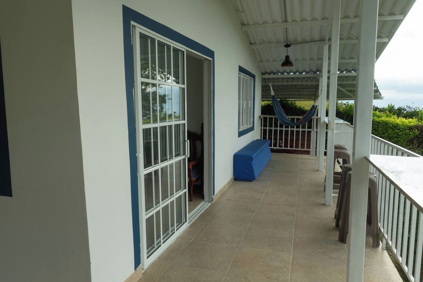 A covered outdoor area with a tiled floor, a blue bench, and a hammock.