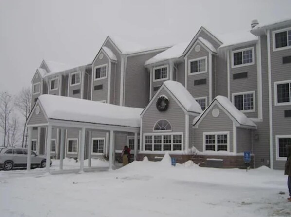 A multi-story building with a covered entrance and a snow-covered ground. - Microtel Inn By Wyndham Parry Sound (Parry Sound)